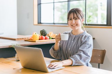 パソコンの前でコーヒーを飲む女性